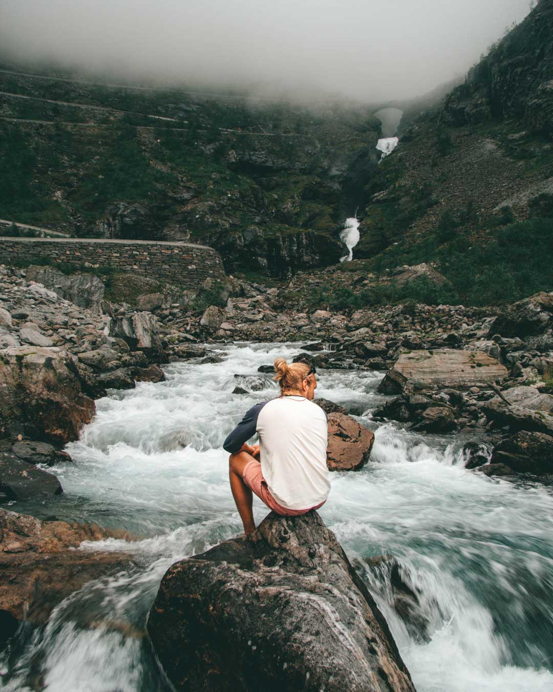 A guy sitting in a waterfall near Trollstigen