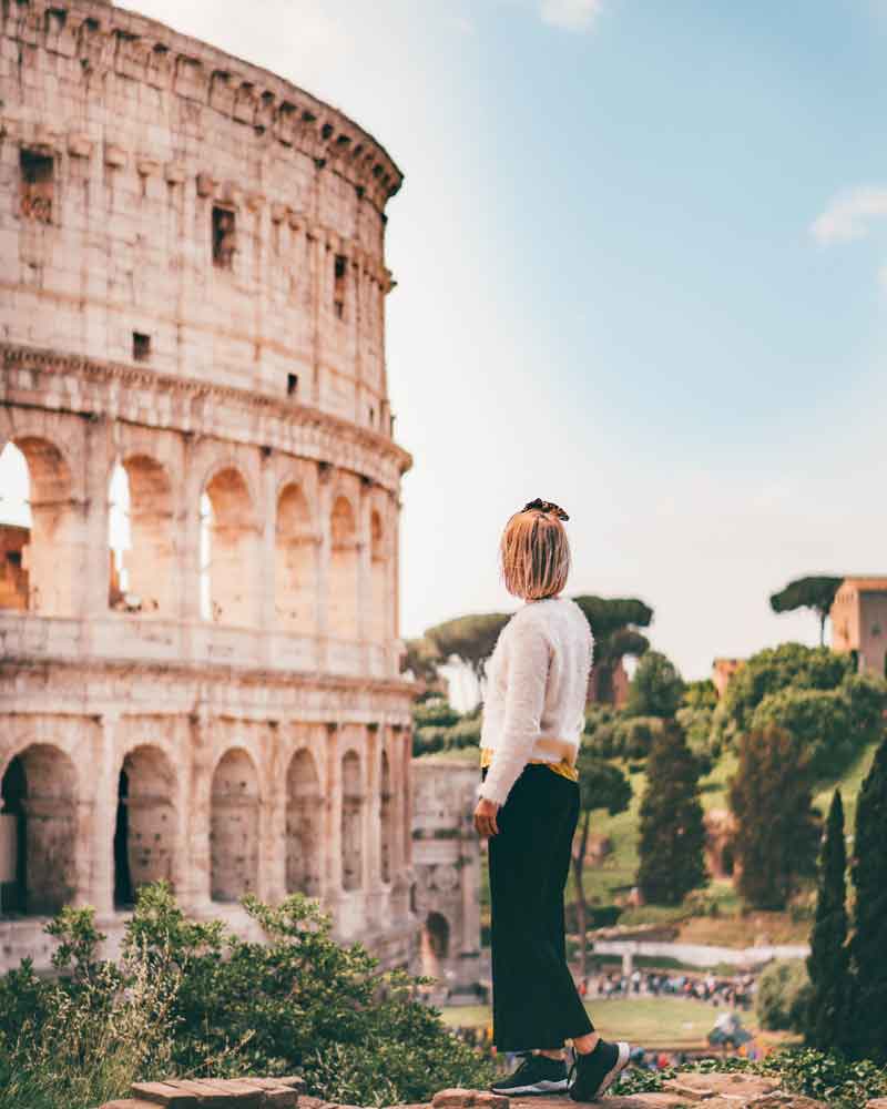 woman standing in front of colosseum in rome, italy