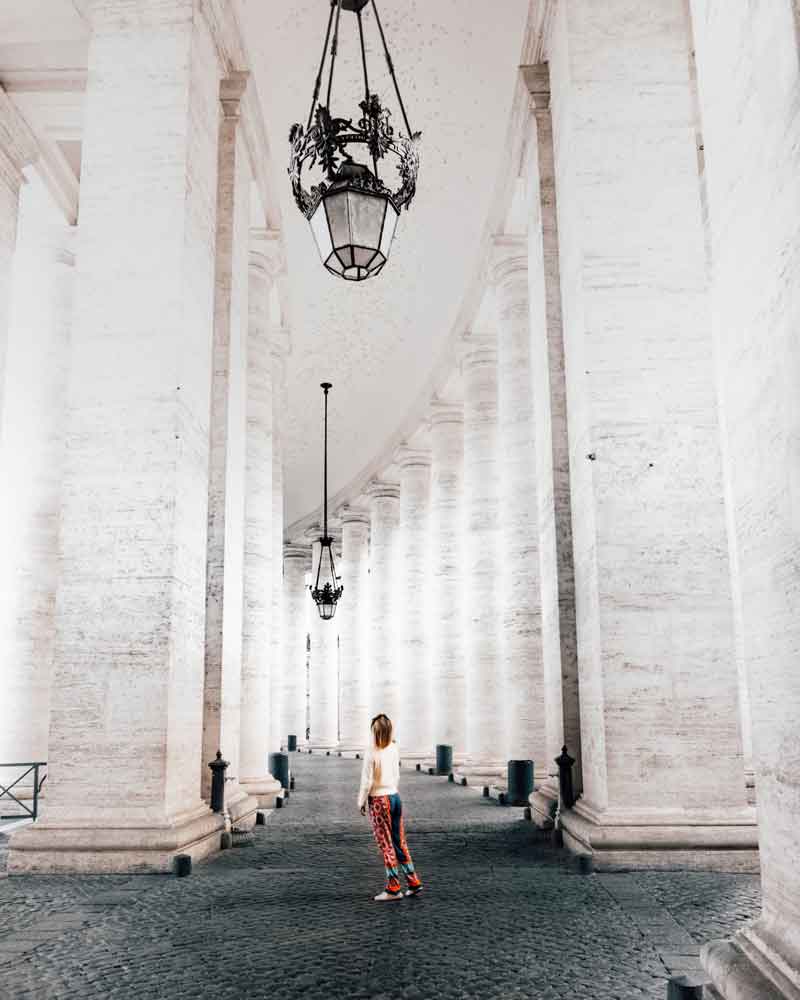 woman standing between the pillars outside st peter's basilica in the vatican city