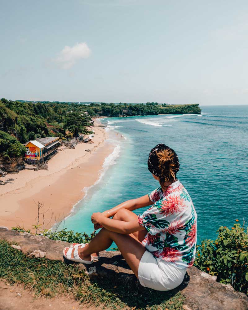 woman sitting on a viewpoint in front of a beach